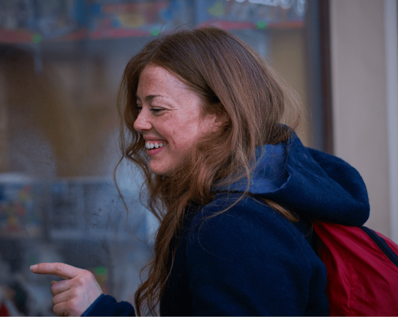 outside image of red haired girl smiling and looking in shop window showing mild to moderate roscea on her cdheets and forward 